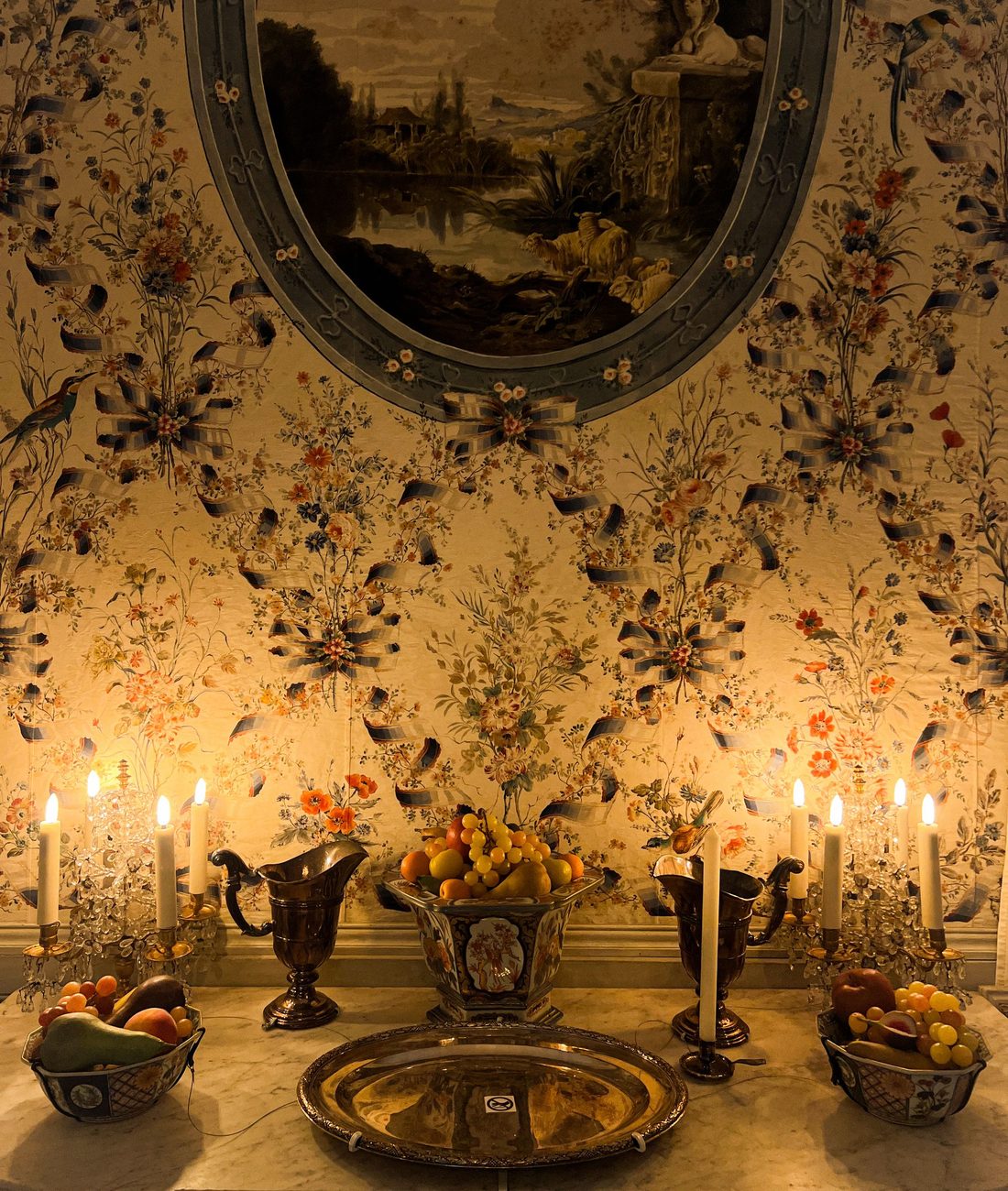 Warm candlelit interior with classic floral wallpaper, reflecting careful craftsmanship