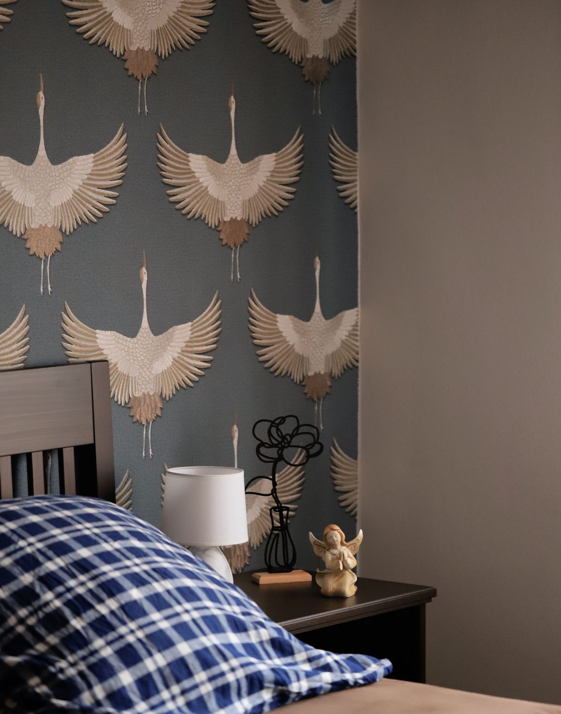 Blue-grey crane and botanical wallpaper as a feature wall behind a bed