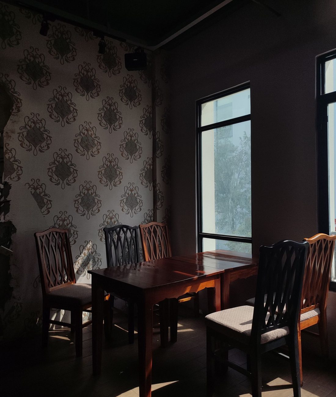 Floral wallpaper wrapping a dining corner with a dark wood table and chairs