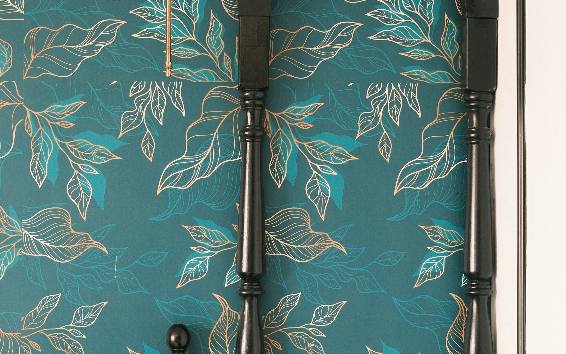 Teal botanical wallpaper with gold leaf detailing in an arched alcove behind an elegant bed